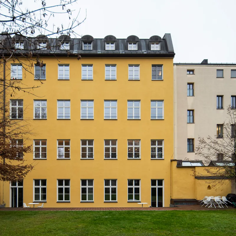  Gütt Old Feldhaus Revitalisierte gelbe Fassade mit Sprossenfenstern, grüner Gartenfläche und Sitzbereich im Hof.